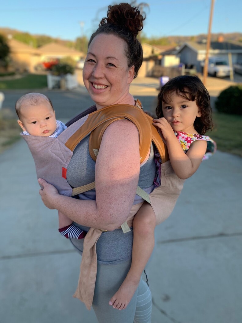 Erin Sricharoon has a baby in a carrying at her front and a toddler on her back.