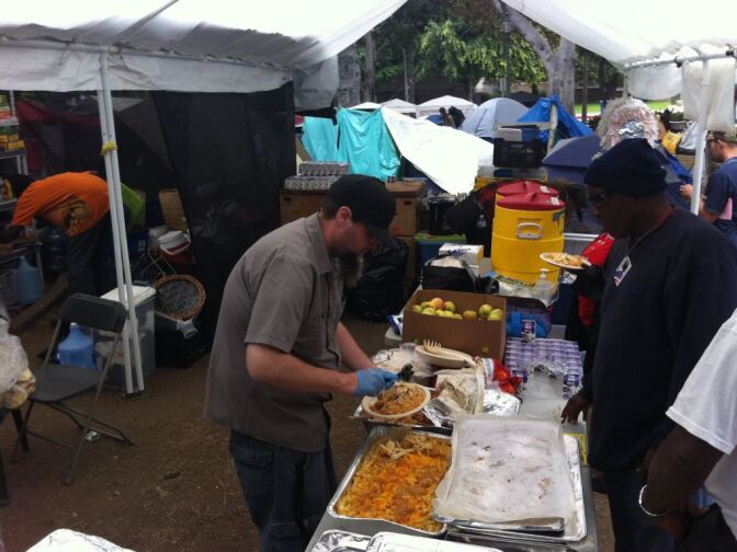 A member of Occupy Los Angeles serves Jennie Cook's catered meal for fellow demonstrators.