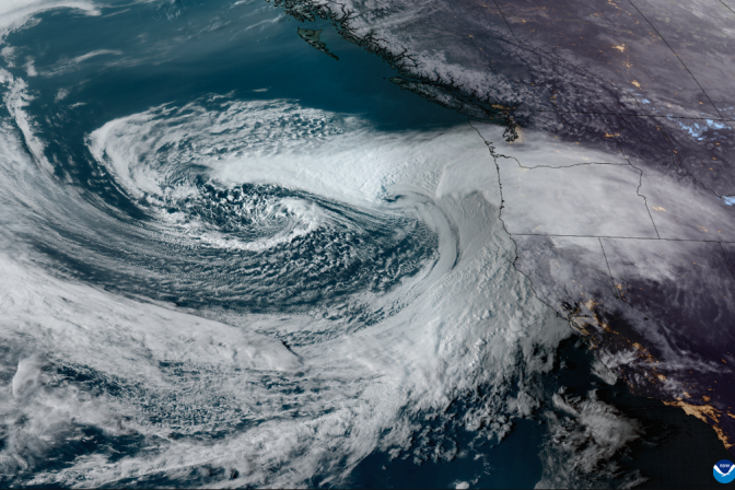 Satellite image of huge swirling white clouds over the ocean and the west coast of the United States