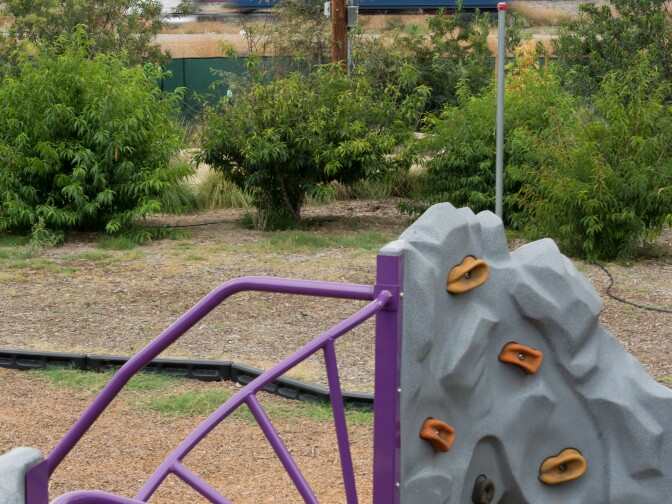 An oil refinery and highway are visible over the fence of a Long Beach child care center. KPCC reporters Deepa Fernandes and Sarah Monte investigate the effect of air pollution on early childhood development by taking air quality readings outside of child care centers located in Los Angeles County.
