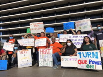 A group of people holding signs poses for a photo. 