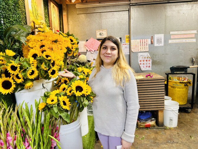 Female persenting person stands next to sunflowers.
