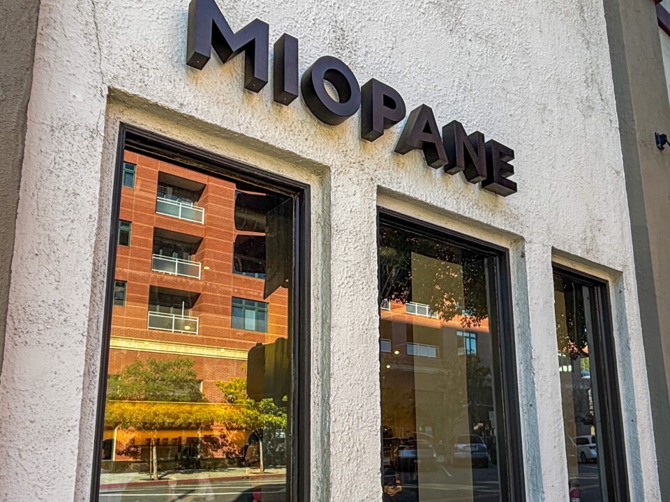 The exterior of Miopane bakery in Old Town Pasadena, with a sign above three windows.d neighboring buildings.