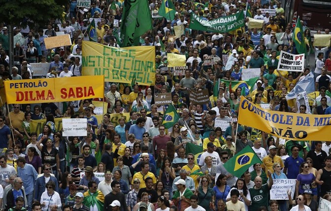 Demonstrators hold banners reading "Institutional crisis in Brazil" and "Dilma knew" as they take part in a protest demanding the impeachment of Brazilian re-elected President Dilma Rousseff in Sao Paulo, Brazil on November 15, 2014. AFP PHOTO / Miguel SCHINCARIOL        (Photo credit should read Miguel Schincariol/AFP via Getty Images)