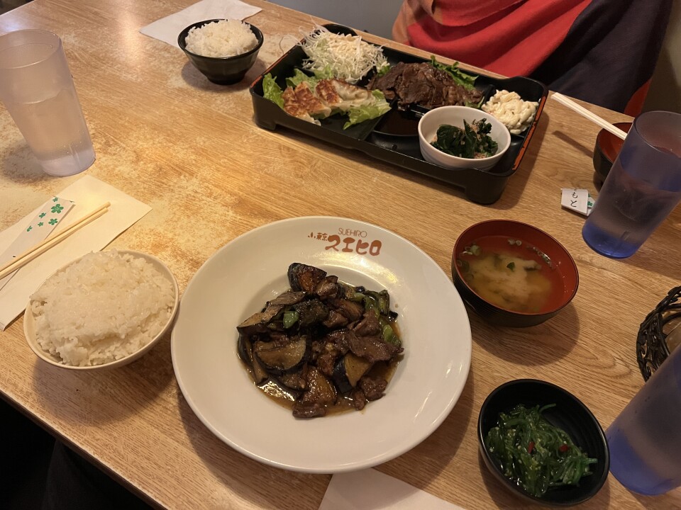 A table filled with several Japanese dishes including a house special of eggplant and beef cooked in a miso sauce.