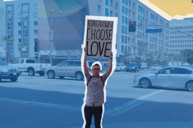 A protester in Koreatown raises a Koreatown Choose Love poster