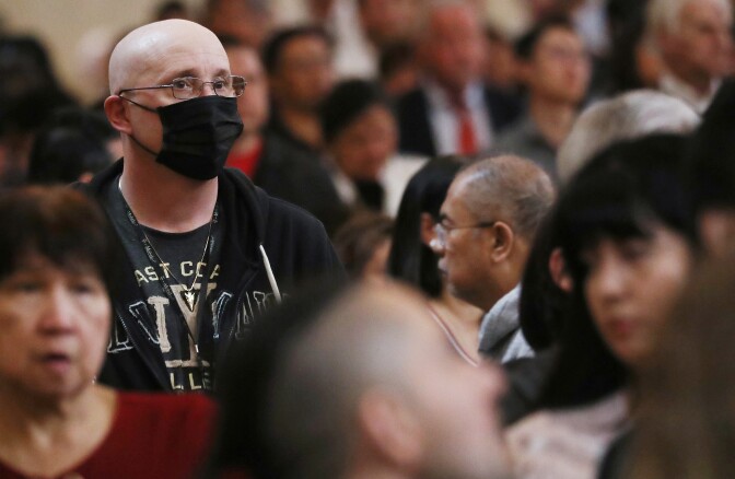 LOS ANGELES, CALIFORNIA - FEBRUARY 26: A worshipper (L) wears a face mask to protect against the coronavirus while sitting in a pew at the Cathedral of Our Lady of the Angels on Ash Wednesday on February 26, 2020 in Los Angeles, California. The worshipper said he was not sick but was wearing the mask out of an abundance of caution. Ash Wednesday marks the beginning of Lent and involves the placing ashes on the foreheads of Christian believers as a sign of repentance which occurs 40 days, excluding Sundays, before Easter.  (Photo by Mario Tama/Getty Images)