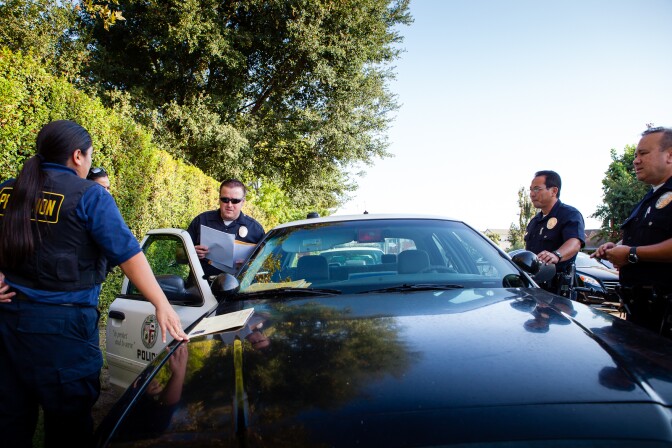 On August 21, 2012, North Hollywood's Probation Compliance Unit discusses the day's next home visit. As part of California's current AB 109 "prison realignment" scheme that gives low-level offenders the possibility of early probation to ease prison over-crowding, the team makes random visits to former prisoners to make sure they are following the terms of their probation.