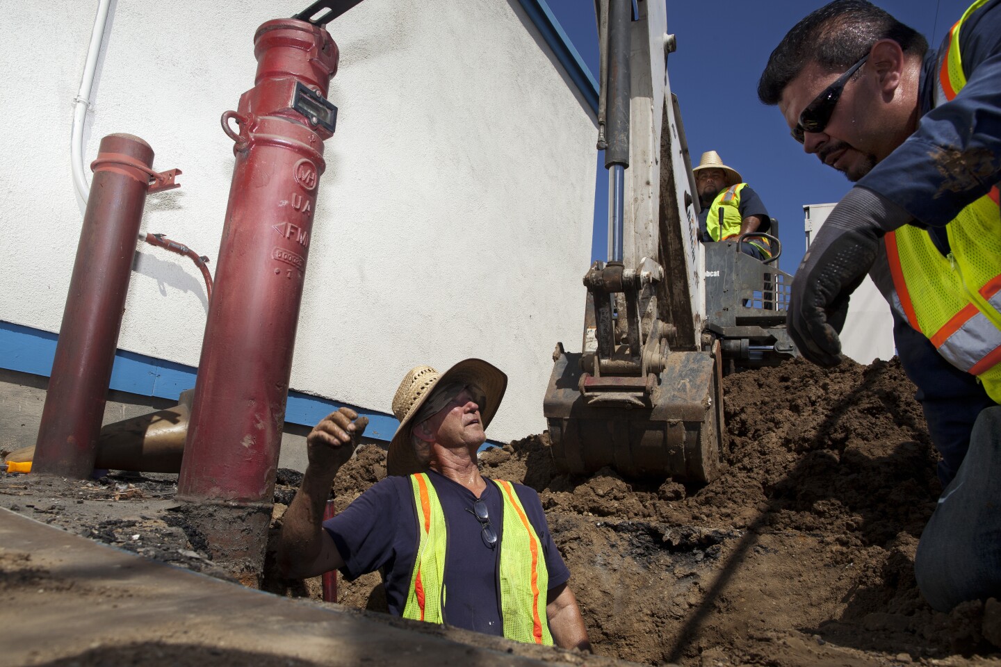 Dan Sapia, left, consults Christopher Cadena while working on a leaking water main at Hoover Street Elementary School. The Los Angeles Unified School District plumbing crew estimated that the repair would take three days. Until the water main feeding the fire sprinklers is fixed, the school has someone on fire watch at all hours of the day.