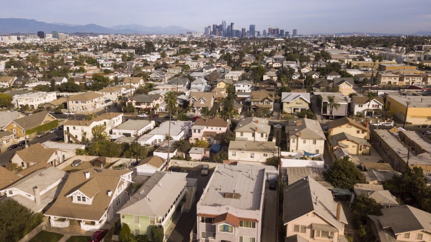 Aerial view of housing in Los Angeles with a view to the city's downtown skyline in the distance.