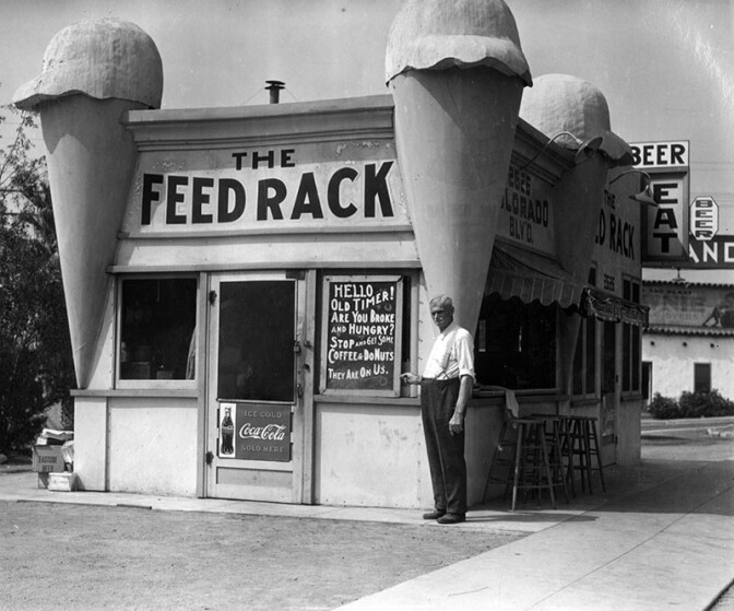 Originally built as an ice cream parlor with an oversized ice cream cone at each corner, the building became the Feed Rack restaurant during the Depression. Notice the sign: "Hello, Oldtimer! Are you hungry? Stop and get some coffee & donuts. They are on us." (circa 1930) (Photo via Los Angeles Public Library Collection)
