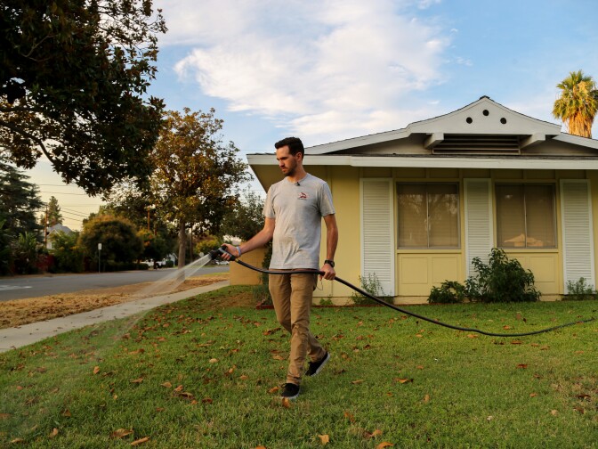 Brandon Miller waters the lawn in front of his Riverside home, July 17, 2018. (Signe Larsen/KPCC) 