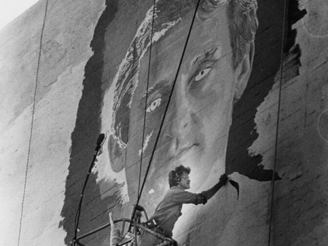 1981: Kent Twitchell leans from a scaffold hanging over the Job Corps Center building at 1031 South Hill Street as he works on his mural "Monument to Ed Ruscha". The mural was completed in 1987. It took nine years to complete and was destroyed without authorization (it was painted over completely) in 2006. 
