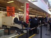Transportation Security Administration screeners pull luggage through an x-ray machine at a security checkpoint near the Southwest Airlines counter at Los Angeles International Airport.