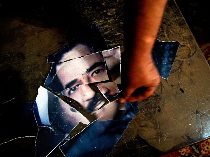 A man puts the torn pices of a photograph of Saddam Hussein back together while waiting for a meeting with officials from the public works deptartment and the police department who are desperatly needed back on duty as the citizens of Bagdad try to restore the citys vital functions in downtown Bagdad Sunday April 13, 2003.