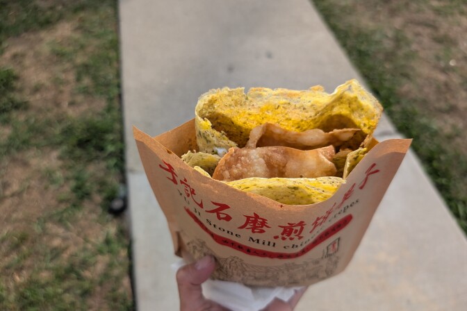 An egg wrap with a fried, crunchy dumpling wrap sticking out from inside.