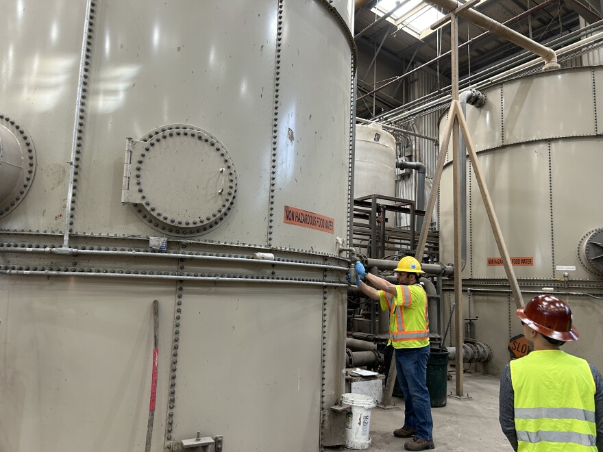 Large off-white circular tanks in a large warehouse. 