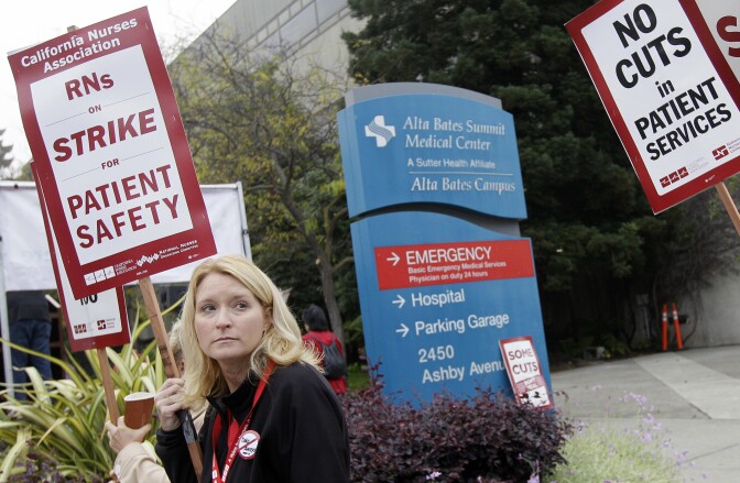 Nurse Kim Conklin holds up a sign as protests with other nurses outside of Alta Bates Medical Center in Berkeley, Calif., Thursday, Sept. 22, 2011. Nurses began picketing Thursday morning outside dozens of Northern and Central California hospitals as part of a one-day strike over benefit cuts and other concessions sought by hospital management. (AP Photo/Jeff Chiu)