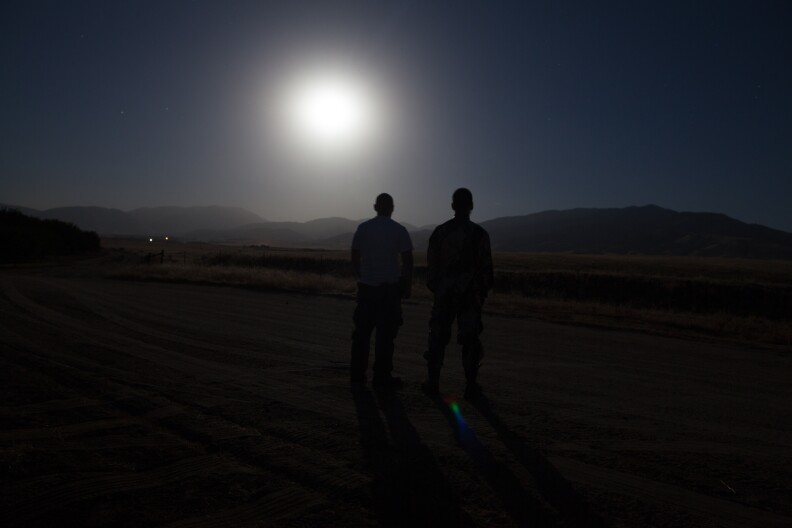 Erik Sun and his friend Eric Leong look at the full moon rising over the hills that the wild pigs live in.