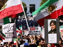 Protesters hold flags, signs and an image of Masha Amini with the words in English and Farsi: Women, life, Freedom