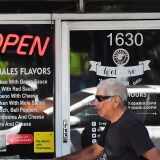 A man walks past a restaurant with an illuminated Open sign on May 5, 2021 in Los Angeles, California. - Los Angeles County is now eligible to move into the yellow Covid-19 tier in California's coronavirus reopening framework - the least restrictive tier - allowing for a gradual return to higher capacity at most businesses. (Photo by Frederic J. BROWN / AFP) (Photo by FREDERIC J. BROWN/AFP via Getty Images)