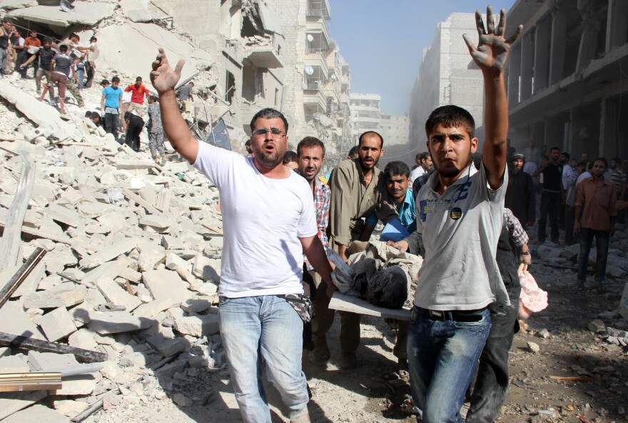 Syrian men evacuate a victim following an air strike by regime forces in the northern city of Aleppo on August 26, 2013. Syria's opposition accused pro-regime forces of opening fire at UN weapons inspectors on their way to a suspected chemical weapons site outside Damascus in a bid to hinder their investigation.
