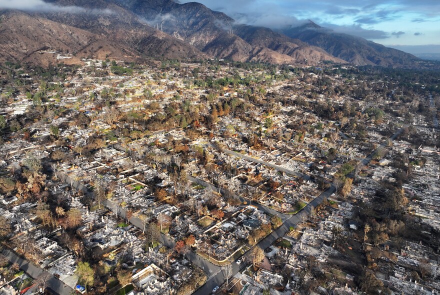 An aerial view of homes that burned in a fire with mountains in the background.