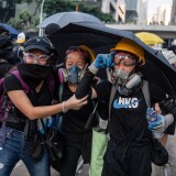 HONG KONG, CHINA - OCTOBER 1: Protesters affected by tear gas flee during clashes with police in Admiralty and Wan Chai on October 1, 2019 in Hong Kong, China. Pro-democracy protesters marked the 70th anniversary of the founding of the People's Republic of China in Hong Kong through demonstrations as the city remains on the edge with the anti-government movement entering its fourth month. Protesters in Hong Kong continue its call for Chief Executive Carrie Lam to meet their remaining demands since the controversial extradition bill has been withdrawn, which includes an independent inquiry into police brutality, the retraction of the word ìriotî to describe the rallies, and genuine universal suffrage, as the territory faces a leadership crisis. (Photo by Laurel Chor/Getty Images)