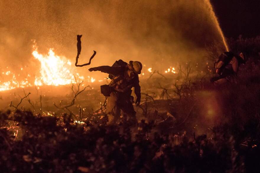 A firefighter works to extinguish the Thomas Fire as it burns past the 101 Highway towards the Pacific Coast Highway in Ventura, California, Dec. 7, 2017.