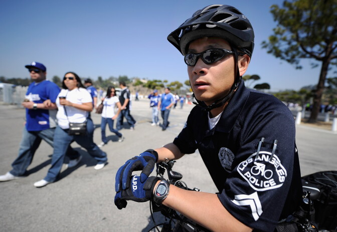 File: A Los Angeles Police Department officer on a bicycle patrols the parking lot of Dodger Stadium prior to the home opener against the Pittsburgh Pirates.