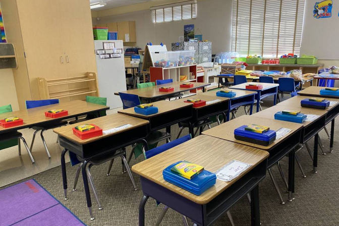 A children's classroom with pencil boxes and desks lined up in rows