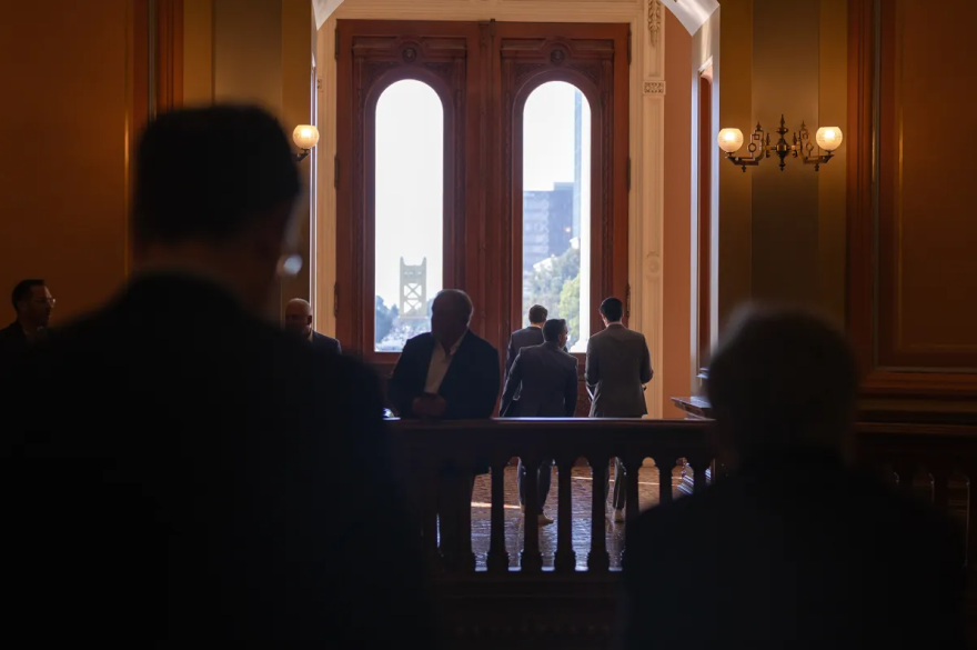 People are walking toward a set of large doors with windows. Two people are out of focus in the foreground looking in that direction.