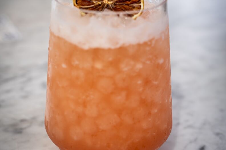 A pink Mai Tai on the rocks with a blood orange garnish.