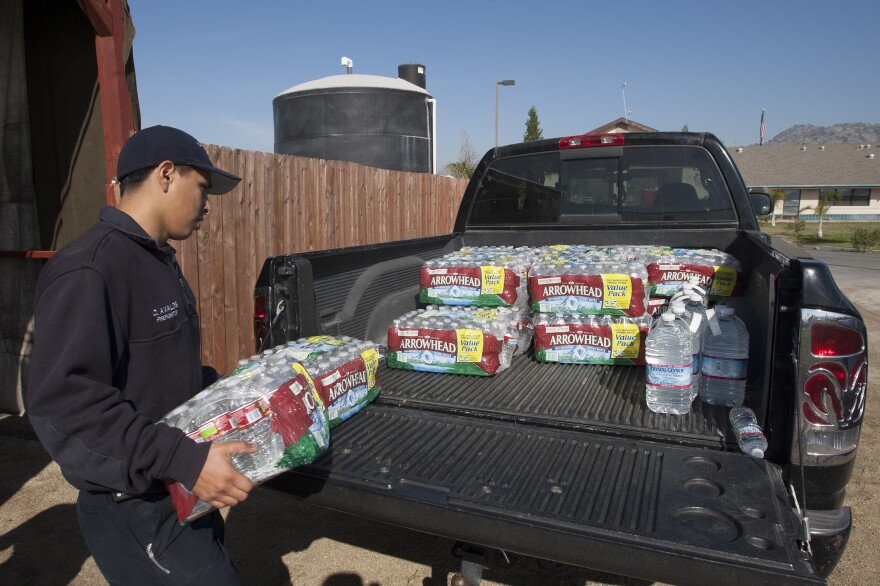 EAST PORTERVILLE, CA - FEBRUARY 11: Volunteer firefighter, Christian Avalos loads bottled water into the bed of a truck for resident Donna Johnson to distribute as water wells supplying hundreds of residents remain dry in the fourth year of worsening drought on February 11, 2015 in East Porterville, California. Many local residents fill water tanks with free non-potable water for flushing toilets, bathing and laundering. Bottled water is used for drinking, cooking and washing dishes. Most of the wells of about 926 dry homes in Tulare County stopped flowing last summer when some 17 California communities ran out of water. (Photo by David McNew/Getty Images)