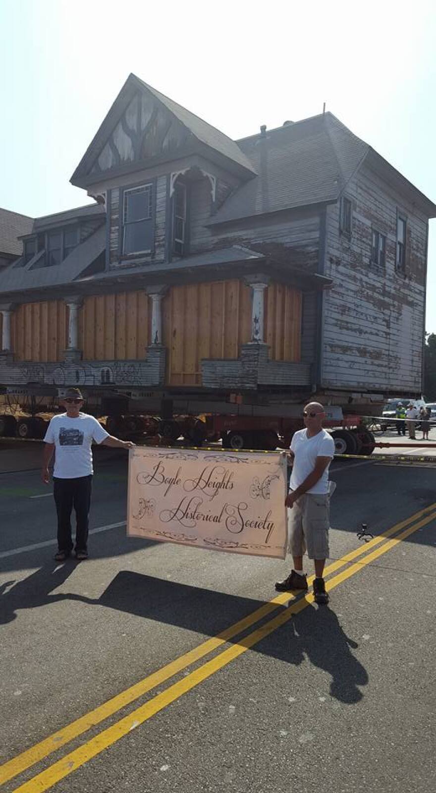 Members of the Boyle Heights Historical Society hold a banner as the 1895 Peabody Werden House is moved across the street on Thursday, June 30, 2016.
