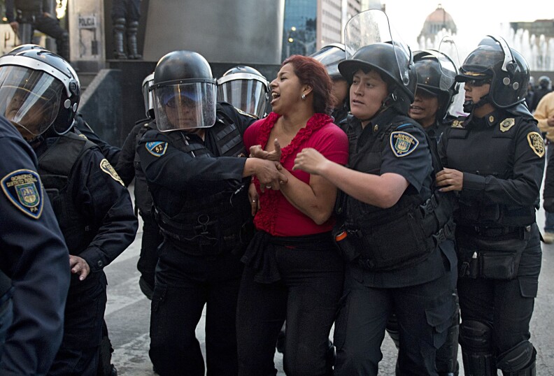 Riot policemen arrest a teacher during a protest against the education reform in Mexico City on November 26, 2013. President Enrique Pena Nieto pushed through Congress changes to the constitution in order to require teachers to undergo mandatory performance appraisals.  AFP PHOTO /  Yuri CORTEZ        (Photo credit should read YURI CORTEZ/AFP/Getty Images)