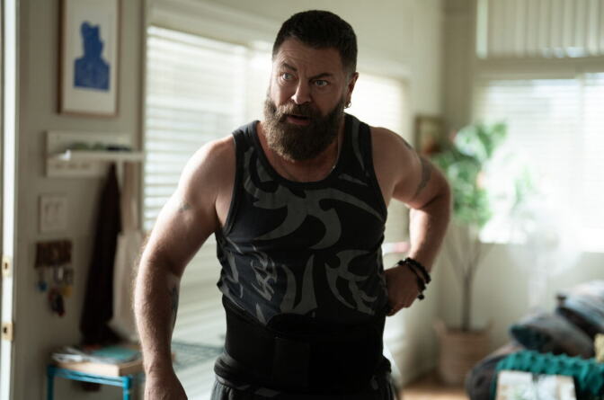 A still from a TV show of a man with a beard and in a tank top.