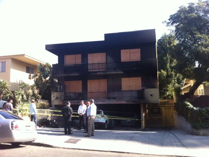 Officials chat in front of 1434 Fuller Ave., one of the buildings damaged by arsonist who set at least 19 fires early Friday morning.