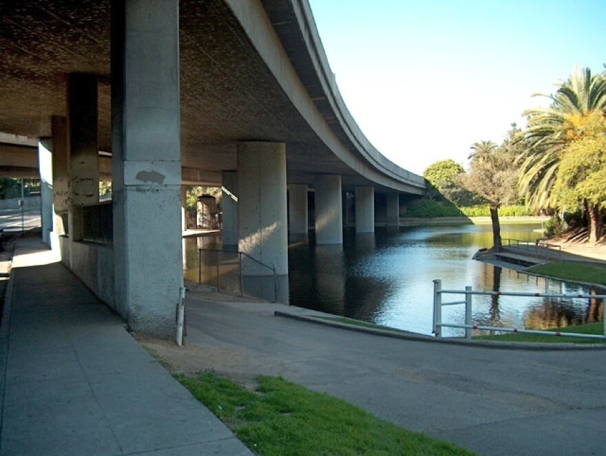 Freeway pilons rise up from the water of a lake in park.