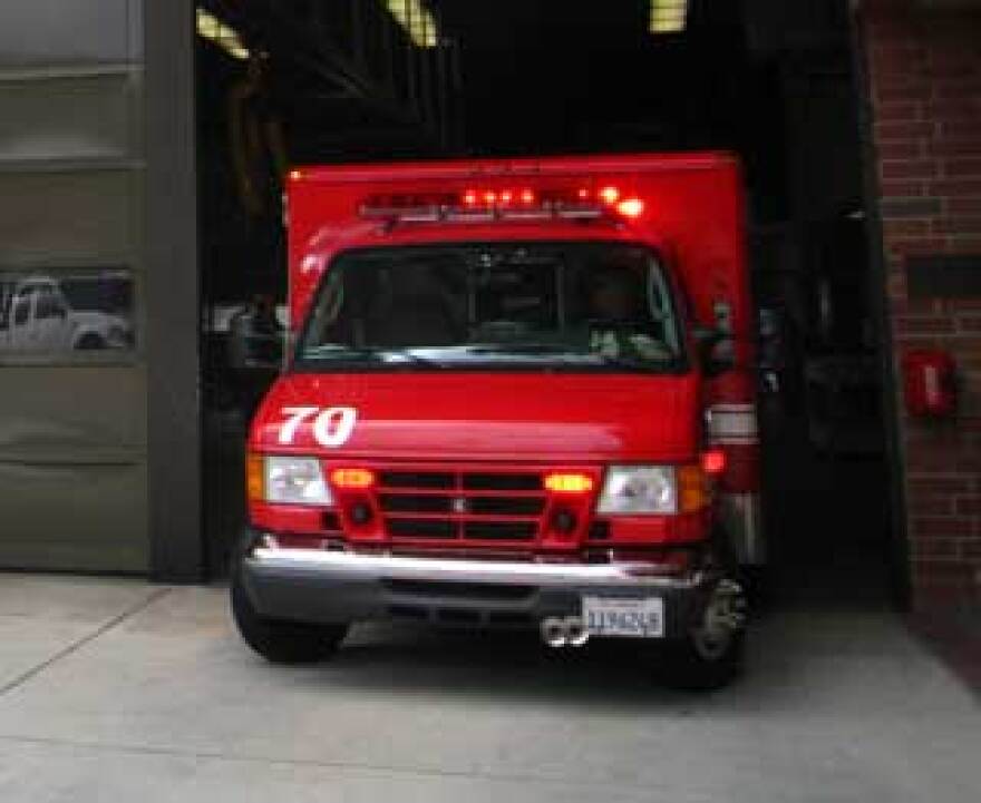 A red ambulance is seen backed into a hospital loading area.