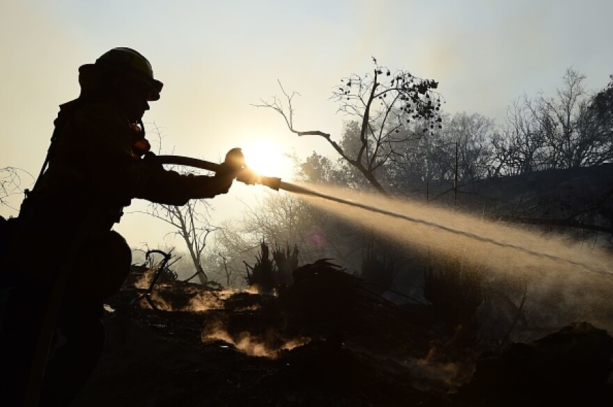 LAFD Firefighter Allen Janzen puts down smoldering embers in the Bel Air neighborhood of Los Angeles while fighting the Skirball Fire on December 6, 2017.
