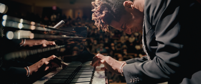 A man in a black coat playing the piano