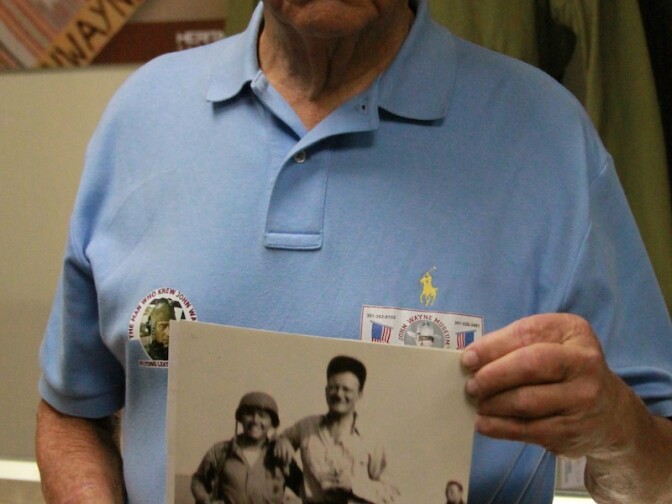 Bill Atkins, 80, holds a blurry photo of himself at age 19 with John Wayne during the filming of “Flying Leathernecks.” Atkins came from Maryland to view the auction.