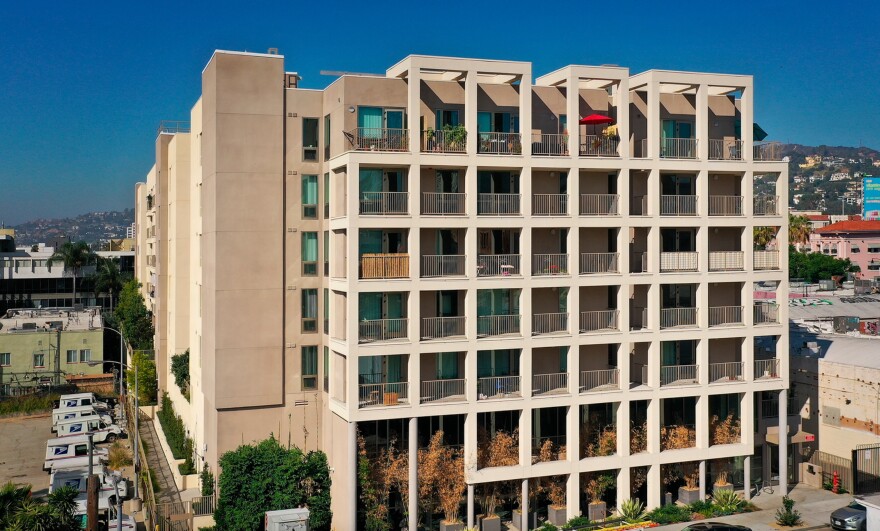 A thick, beige building with multiple floors boasts a "grid-like" framework on the side facing the camera.