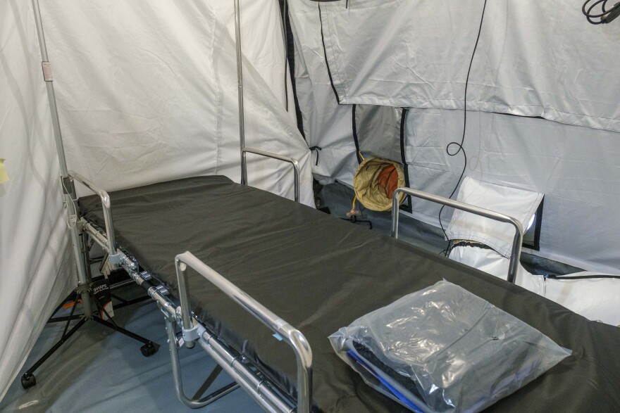 A hospital gurney is located inside a white tent