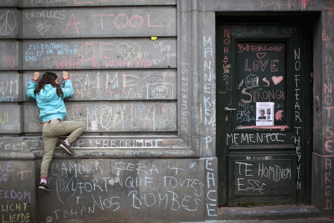 BRUSSELS, BELGIUM - MARCH 23:  A young girl climbs a wall to chalk a message of support on the the Bourse De Brussels building in the Place de la Bourse following yesterday's terrorists attacks on March 23, 2016 in Brussels, Belgium. Belgium is observing three days of national mourning after 34 people were killed in a twin suicide blast at Zaventem Airport and a further bomb attack at Maelbeek Metro Station. Two brothers are thought to have carried out the airport attack and an international manhunt is underway for a third suspect. The attacks come just days after a key suspect in the Paris attacks, Salah Abdeslam, was captured in Brussels.  (Photo by Christopher Furlong/Getty Images)
