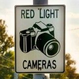 Cars drive past a red light camera sign in Laurel, Maryland.
