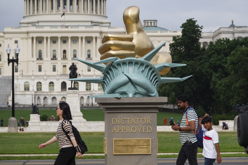 A statue has the top of the Statue of Liberty with a gold hand with a thumbs up.
