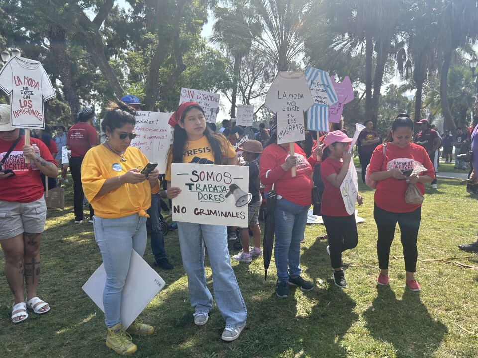 People stand on a lawn holding signs in Spanish.
