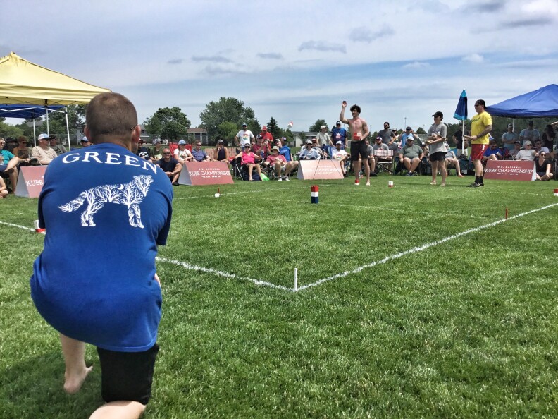 People standing around a lawn. Small blocks are placed on the field.
